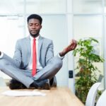 A man sitting on top of a table meditating an example of Practical Ways to Improve Work-Life Balance