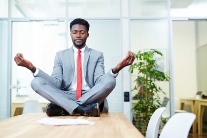 A man sitting on top of a table meditating an example of Practical Ways to Improve Work-Life Balance