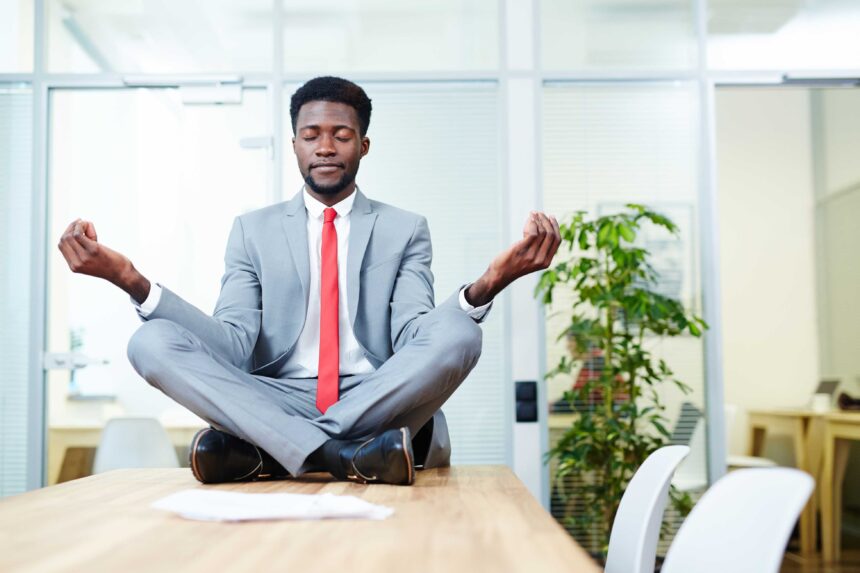 A man sitting on top of a table meditating an example of Practical Ways to Improve Work-Life Balance
