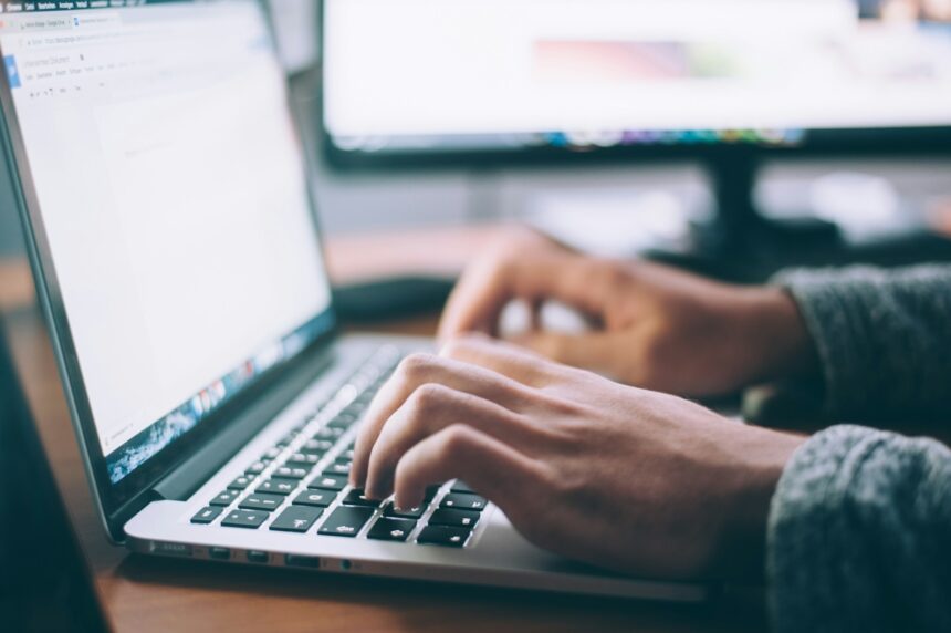 A hand typing on a computer. Image for Importance of Website for Business