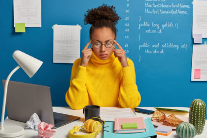 Curly haired student keeps both fingers on temples, tries to gather with thoughts, recalls information in mind